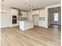 Open-concept kitchen features white cabinets, stainless appliances and hardwood flooring at 8022 Franklin Trail St, Mint Hill, NC 28227