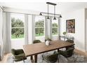 Bright dining room with wood table, green chairs, and large windows overlooking a garden at 8026 Cedarsmith Ct, Charlotte, NC 28217