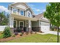 Inviting two-story home with a covered front porch featuring stone accents and manicured landscaping at 8230 Verona Rd # 80, Charlotte, NC 28213