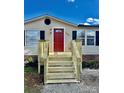 Mobile home with a red door and new wooden stairs at 9763 Knightbridge Dr, Concord, NC 28025