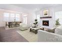 Inviting living room featuring a cozy fireplace, large windows for natural light, and an open view to the dining area at 1364 Cedardale Ln, Denver, NC 28037