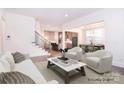 Spacious living room with hardwood floors, neutral tones, staircase, and seamless transition to kitchen and dining areas at 1364 Cedardale Ln, Denver, NC 28037