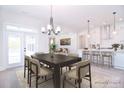 Open dining area with a modern chandelier, dark wood table, and access to the kitchen at 1374 Cedardale Ln # 33, Denver, NC 28037