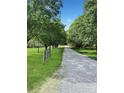 Long gravel driveway lined with mature trees and lush green grass, leading to a secluded and inviting home at 1769 Old Nc 27 Hwy, Mount Holly, NC 28120