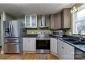 Modern kitchen features stainless steel appliances, gray cabinetry, and wood flooring at 6726 Wannamaker Ln, Charlotte, NC 28226