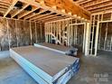 Unfinished interior with stacked drywall sheets ready for installation, revealing framing and insulation at 13312 Chopin Ridge Rd, Huntersville, NC 28078