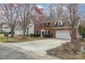 A beautiful two-story brick home with black shutters, surrounded by mature trees and a green lawn at 6654 Kingbird Ct, Charlotte, NC 28215