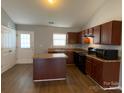 Modern kitchen with dark brown cabinets, an island, and a full suite of appliances at 104 Lassiter Ct, Mount Holly, NC 28120