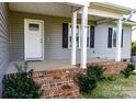 Inviting front porch with brick steps, white pillars, and a storm door entrance at 118 Cypress Acres Ln, Statesville, NC 28625