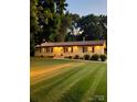 Inviting single-story home with a manicured lawn and warm exterior lighting at dusk at 206 Fox Den Rd, Troy, NC 27371