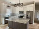 Bright kitchen with white cabinets, stainless steel appliances, a marble countertop island and modern light fixture at 5743 Selkirk Dr, Hickory, NC 28601