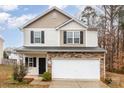 Two-story home showcasing stone accents and a two-car garage against a bright sky backdrop at 6204 Springbeauty Dr, Charlotte, NC 28227