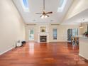 Bright living room with hardwood floors, a fireplace, vaulted ceilings, and natural light from skylights at 9903 Southampton Commons Dr, Charlotte, NC 28277