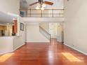 Spacious living room with hardwood floors, staircase, and a balcony overlooking the open-concept design at 9903 Southampton Commons Dr, Charlotte, NC 28277
