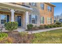 Front entry with stone and brick exterior, navy door, and lush landscaping at 4008 Pinot Way, Indian Land, SC 29707