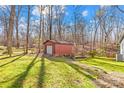 Red storage shed with garage door located on a grassy area with a wooden fence at 911 Wildwood Dr, Kings Mountain, NC 28086