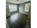 Bright bedroom featuring wood-look flooring, two windows for natural light, and freshly painted walls at 2801 Cowles Rd, Charlotte, NC 28208