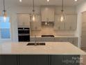 Modern kitchen with gray cabinets, white quartz island, and stainless steel appliances at 7050 Wayfarer Dr # 0085, Charlotte, NC 28269