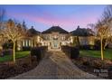 Elegant home with a beautifully landscaped walkway, stunning architecture, and warm exterior lighting at 3042 Kings Manor Dr, Weddington, NC 28104