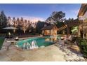 A beautiful outdoor pool area with a cabana, patio, basketball court, and fire bowls at dusk at 3042 Kings Manor Dr, Weddington, NC 28104