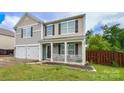 Charming home with inviting porch, and a two-car garage, complemented by a manicured lawn and privacy fence at 11677 Striker Ln, Midland, NC 28107