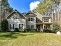 Charming two-story home boasts a welcoming front porch, lush lawn, mature trees, and neat landscaping at 250 Kenway Loop, Mooresville, NC 28117