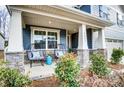 Inviting front porch with stylish outdoor seating and stone accents on the columns with well landscaped yard at 9831 Quercus Ln, Huntersville, NC 28078