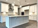 A modern kitchen with white cabinets, a large island, and stainless steel appliances at 9831 Quercus Ln, Huntersville, NC 28078