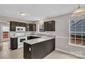 Modern kitchen featuring granite counters, white appliances, dark cabinets, and tiled flooring at 8702 Wood Sorrel Ct, Matthews, NC 28105