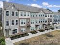 A view of gray townhouses featuring brick accents, symmetrical windows, and landscaped front yards on a sunny day at 2013 Federation Ct, Charlotte, NC 28205