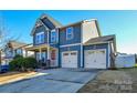 Two-story house featuring gray siding, a two-car garage, and a well-manicured lawn at 4418 Huntley Glen Dr, Pineville, NC 28134