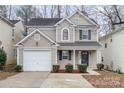 Two-story house with beige siding, a white garage door, and neatly landscaped front yard at 2604 Cochrane Dr, Charlotte, NC 28269