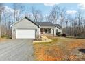 Gray house with attached garage and stone accents, nestled in a wooded setting at 34466 Lisa Dr, Albemarle, NC 28001