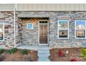 Townhome's front entrance with stonework, a brown door, and landscaping at 638 Sagecroft Ln, Indian Trail, NC 28079