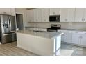 Bright kitchen features a large island, stainless steel appliances, granite countertops and white cabinets at 116 Sentinel Ct, Mooresville, NC 28115