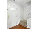 Front entry with hardwood floors, white door, and carpeted stairs at 7724 Autumnview Ct, Huntersville, NC 28078