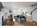 Virtually staged living room with hardwood floors, fireplace, and stairs at 9451 Bonnie Briar Cir, Charlotte, NC 28277
