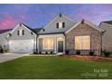 Home exterior featuring dusk lighting, a well-kept lawn, and a welcoming facade at 3111 Vermillion Dr, Harrisburg, NC 28075