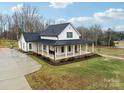 White farmhouse with black roof, spacious yard, and a long driveway at 243 Reese Wilson Rd, Belmont, NC 28012