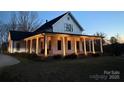 Two-story farmhouse with large front porch, lit at night at 243 Reese Wilson Rd, Belmont, NC 28012