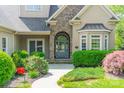 Up close view of the front door, showing stone detail, arched entryway, and manicured landscaping at 4150 Summit Ridge Ln, Denver, NC 28037