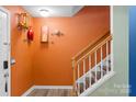 Staircase and orange wall in entryway with floating shelves at 4291 Melrose Club Dr, Matthews, NC 28105