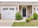 Townhome's front entrance with black door, landscaping, and white garage door at 11315 Savannah Creek Dr, Charlotte, NC 28273