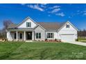 Inviting one-story home with stone and white siding, green shutters, a covered front porch, and a lush green lawn at 3432 Greene Rd, Monroe, NC 28110