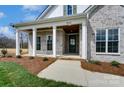 Stunning home entrance with stone accents, white pillars, and a stained wood ceiling on the covered porch at 3432 Greene Rd, Monroe, NC 28110