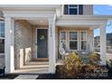 Inviting front porch with gray door and hanging chairs at 14004 Fiery Mist Way, Huntersville, NC 28078