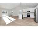 Bright kitchen with white cabinets, stainless appliances, island, and sliding glass door to backyard at 4119 Pebblebrook Sw Cir, Concord, NC 28027