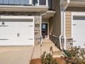 A close-up of a townhome entrance with a stone facade, dark door, and manicured landscaping at 113 Quartz Hill Way, Waxhaw, NC 28173