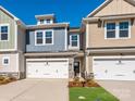 A daytime view of townhomes featuring stone accents, attached garages, and well-maintained landscaping at 113 Quartz Hill Way, Waxhaw, NC 28173