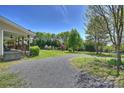 Gravel driveway leading to a well-maintained home with a covered porch and spacious front yard at 16415 Capps Rd, Charlotte, NC 28278